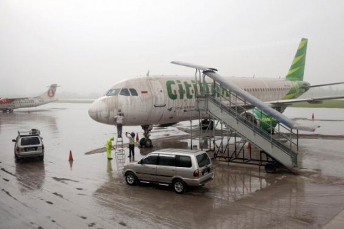 Workers stand near a Citilink airplane covered with ash from Mount Kelud at Adi Sucipto airport in Yogyakarta
