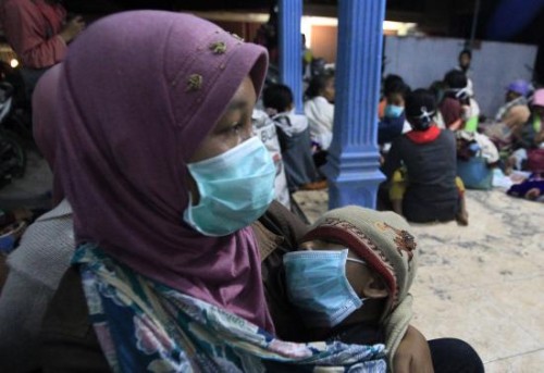A villager who was evacuated from her home due to Mount Kelud's eruptions, holds her daughter at a temporary shelter at Sumber Agung village in Kediri