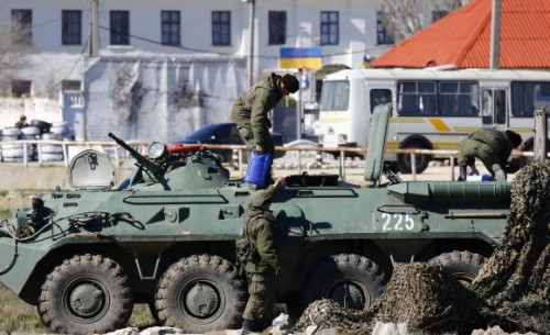 Armed men, believed to be Russian servicemen, supply an armoured personnel carrier (APC) in front of a Ukrainian marine base in the Crimean port city of Feodosia