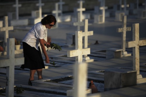 Μια γυναίκα αφήνει λουλούδια στον τάφο ενός Έλλαδίτη  στρατιώτη που σκοτώθηκε στο τουρκική εισβολή του 1974 στην Κύπρο στο στρατιωτικό κοιμητήριο Τύμβος της Μακεδονίτισας 