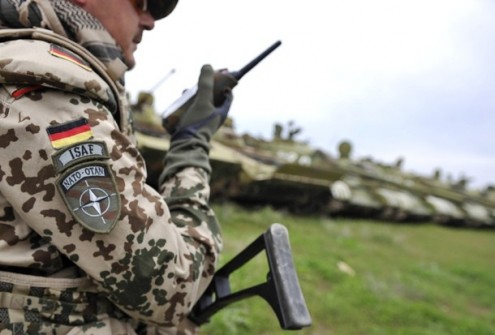 A soldier of the German armed forces Bundeswehr listens to his walkie talkie as he patrols near wreckage from Soviet-Afghan war, outside the German army camp in Kunduz