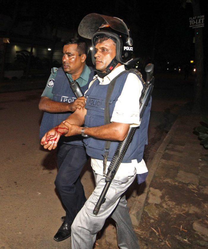 epa05402229 An injured police officer is escorted by a colleague after suffering wounds from a crude bomb blasted by suspected criminals at a Spanish resturant in Dhaka, Bangladesh, late 01 July 2016. Two police officials have been killed during the encounter while some gunmen reportedly took several people hostage, including some foreigners, inside a Spanish resturant. The law inforcement officials try to negotiate with the gunmen while the US-based SITE Intelligence Group quoted the Amaq News Agency as saying that fighters of the terrorist organisation 'Islamic State' (IS) carried out the attack. EPA/STRINGER