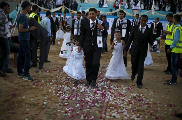 Palestinian girls accompany grooms as they walk separate from the brides during a mass wedding for 150 couples in Beit Lahiya town in the northern Gaza Strip July 20, 2015. The wedding was funded by al-Basheer Society for Relief and Development. REUTERS/Suhaib Salem