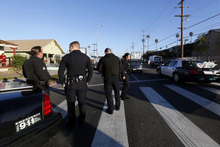 Los Angeles police officers investigate a shooting in South Central Los Angles on Monday, Dec. 29, 2014. A man fired a rifle at two Los Angeles officers in a patrol car on Sunday night but no one was injured in the attack that comes amid tension nationwide between police and protesters rallying against their tactics. LAPD spokeswoman Officer Nuria Venegas said Monday that one man was under arrest and a second suspect was being sought in the shooting in an area of the city ridden with gangs and crime and heavily patrolled by police. (AP Photo/Nick Ut)