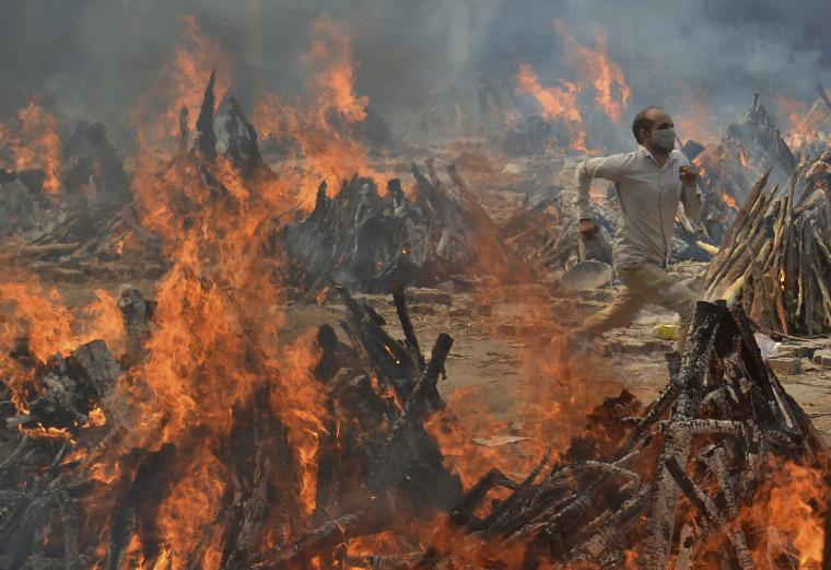 Ένας άντρας τρέχει για να γλιτώσει από την θερμότητα που προκαλούν μαζικές καύσεις νεκρών που έχασαν τη ζωή τους από την Covid-19 στο Νέο Δελχί της Ινδίας τον Απρίλιο του 2021 