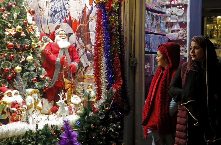 Ιρανοί περνούν μπροστά από ένα κατάστημα που πωλεί χριστουγεννιάτικα στολίδια στην πρωτεύουσα Τεχεράνη στις 25 Δεκεμβρίου 2022