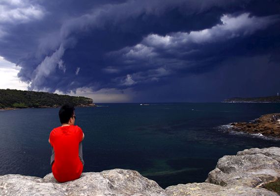 A Chinese tourist watches storm clouds moving along the coast towards the city of Sydney, Australia