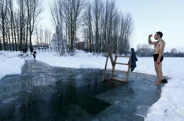 Man crosses himself as he is ready to dip into the icy waters of a lake as part of celebrations for Orthodox Epiphany in Minsk
