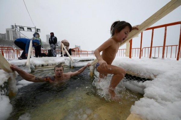A man and a girl take a dip in icy waters during celebrations for the Orthodox Epiphany in the Sea of Japan in Vladivostok