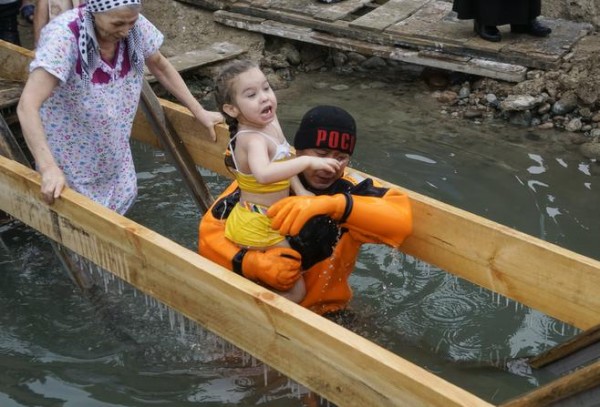 An emergency rescuer carries a child after bathing during Epiphany celebration at the Bolshaya Almatinka river bank in Almaty