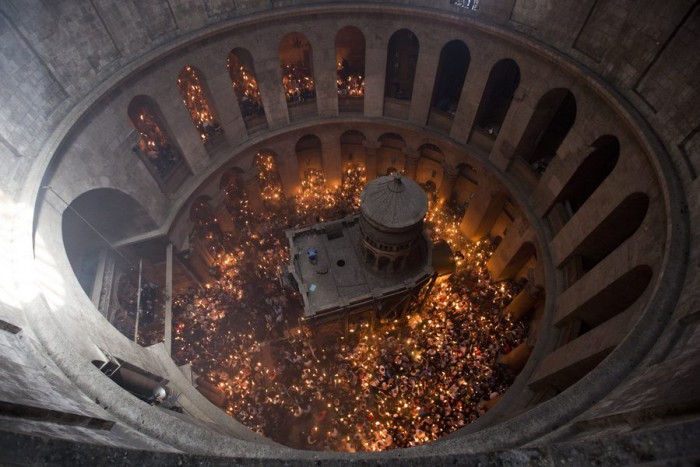 epa05284065 An image taken with a wide angle lens of Orthodox Christian worshippers holding candles at the Tomb of Christ as the miracle of the Holy Fire occurs in the Church of the Holy Sepulchre, Jerusalem, Israel, 30 April 2016. Eastern Orthodox Christians believe the Holy Fire, which emenates from within the Tomb of Christ and quickly spreads around the church and outside to Jerusalem and even to foreign countries, represents the flame of the Resurrection power, as well as the fire of the Burning Bush of Mount Sinai. EPA/ABIR SULTAN