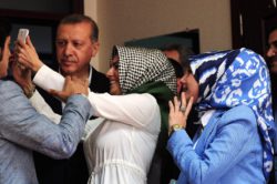 An election official (C) takes a selfie photo with Turkish President Recep Tayyip Erdogan (L) after he cast his ballot in Turkey's legislative election in Istanbul on June 7, 2015. Turkish voters went to the polls on June 7 in a bitterly-contested election set to determine whether President Recep Tayyip Erdogan can tighten his increasingly controversial grip on the country. AFP PHOTO / OZAN KOSE