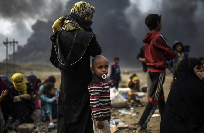 Iraqi families who were displaced by the ongoing operation by Iraqi forces against jihadists of the Islamic State group to retake the city of Mosul, are seen gathering in an area near Qayyarah on October 24, 2016. The UN refugee agency is preparing to receive 150,000 Iraqis fleeing fighting around the Islamic State group-held city of Mosul within the next few days, its chief said. / AFP PHOTO / BULENT KILIC